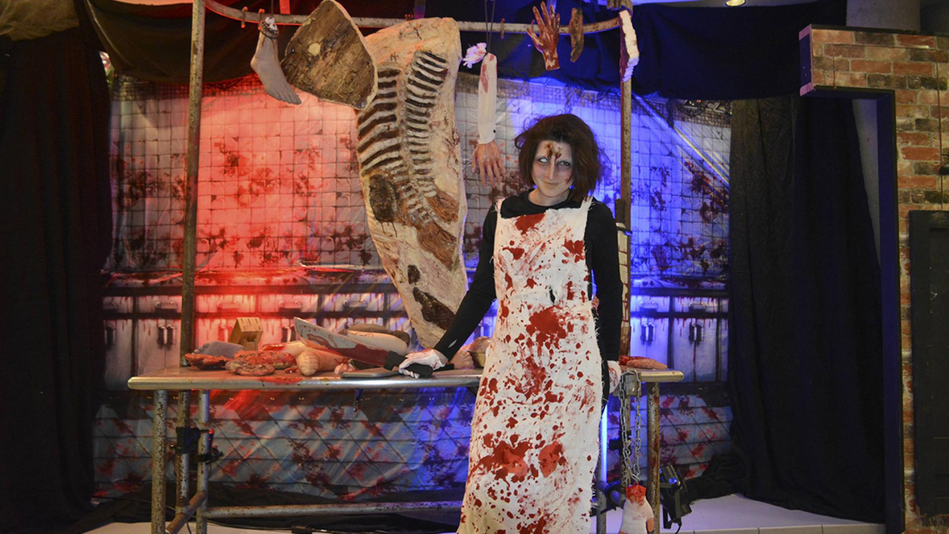 Scary blood covered lady with butchered body parts hanging behind her.