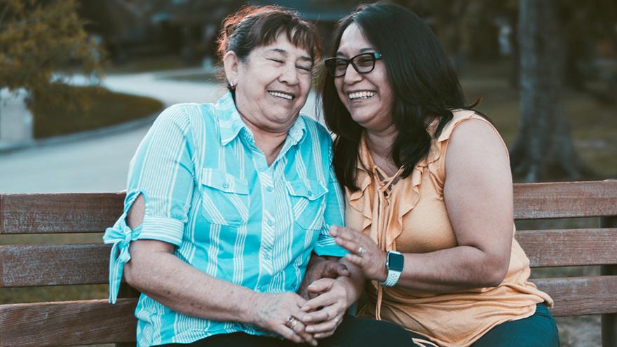 Family members smiling and talking on a bench