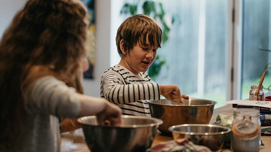 Siblings mixing flour in the kitchen.
