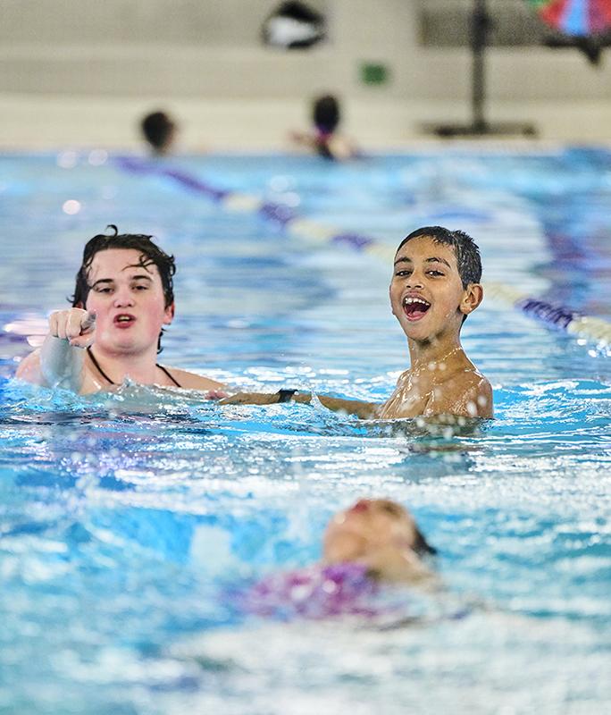Lifeguard swimming with 2 happy smiling kids