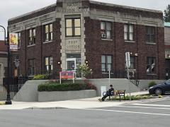 A man sits in front of the historic Mission City Post Office Built in 1935