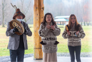 three people singing and drumming